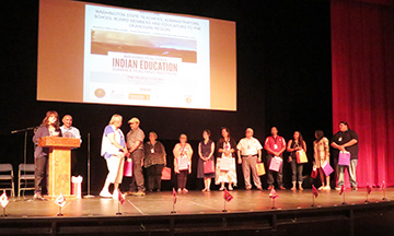 The planning committee members of the first Summer Teaching Institute stand together on a stage