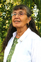 A picture of Jeannette Armstrong standing outside beneath a tree.