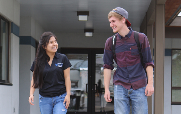 Female latina student walking with white male student